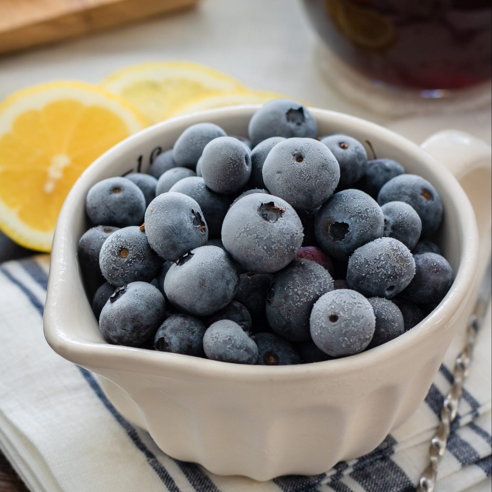 freeze produce with blueberries in a white bowl with lemon slices on the side