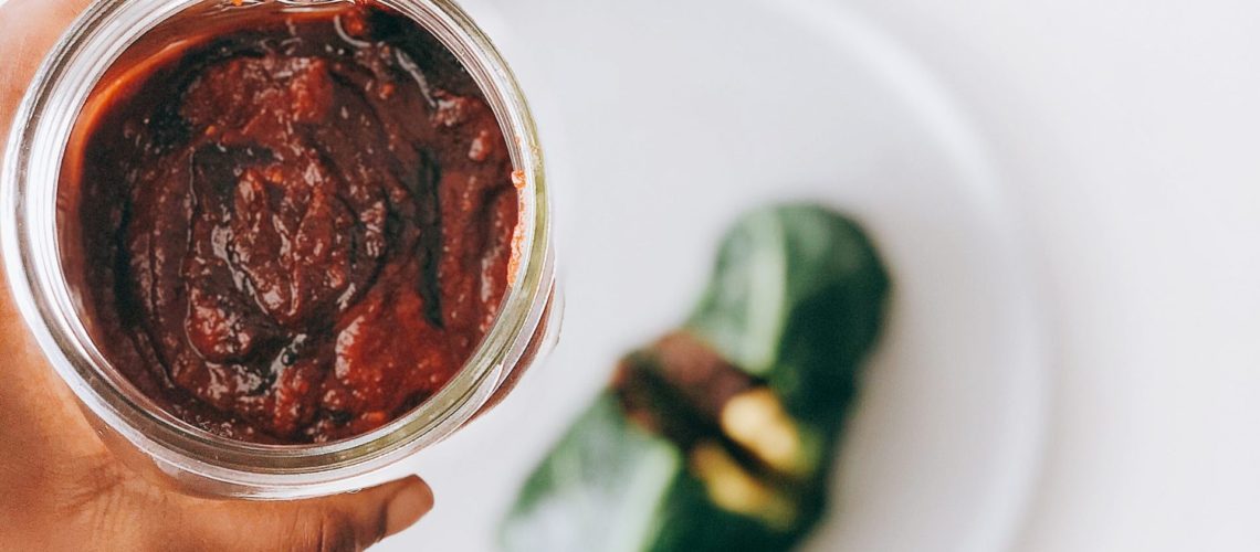 Date-Sweetened barbecue sauce in a mason jar with collard wraps